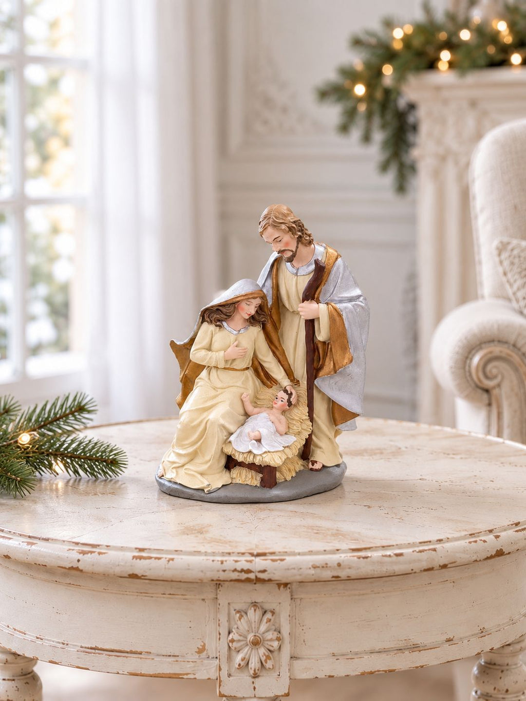 Crèche de Noël sur une table ronde patinée dans un salon lumineux, près d’un fauteuil en lin.