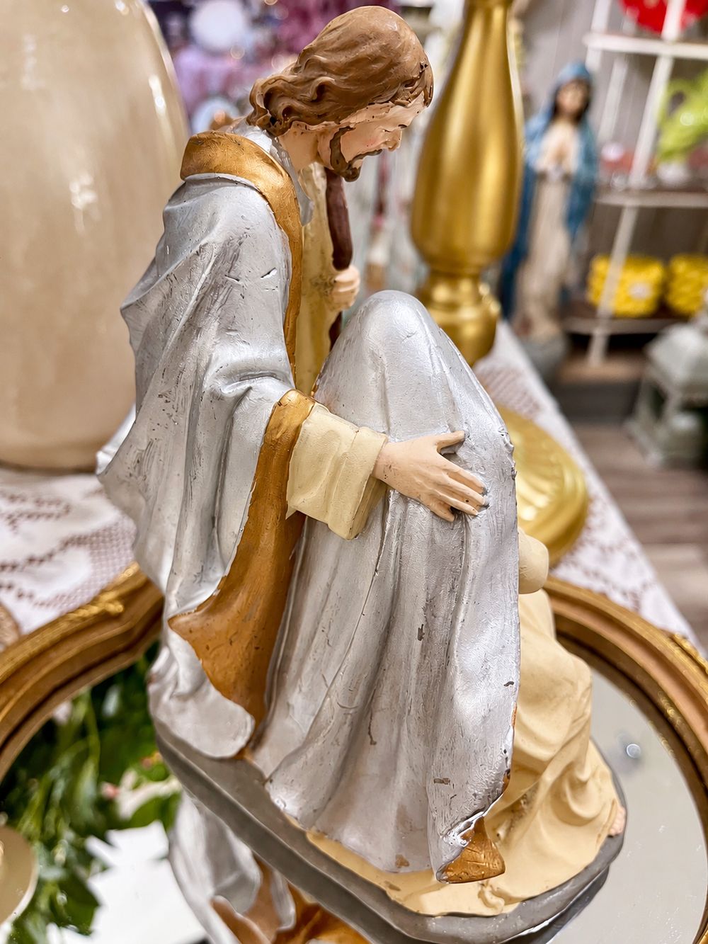 Vue arrière de la crèche de Noël montrant les manteaux argentés, les bordures dorées et la patine.