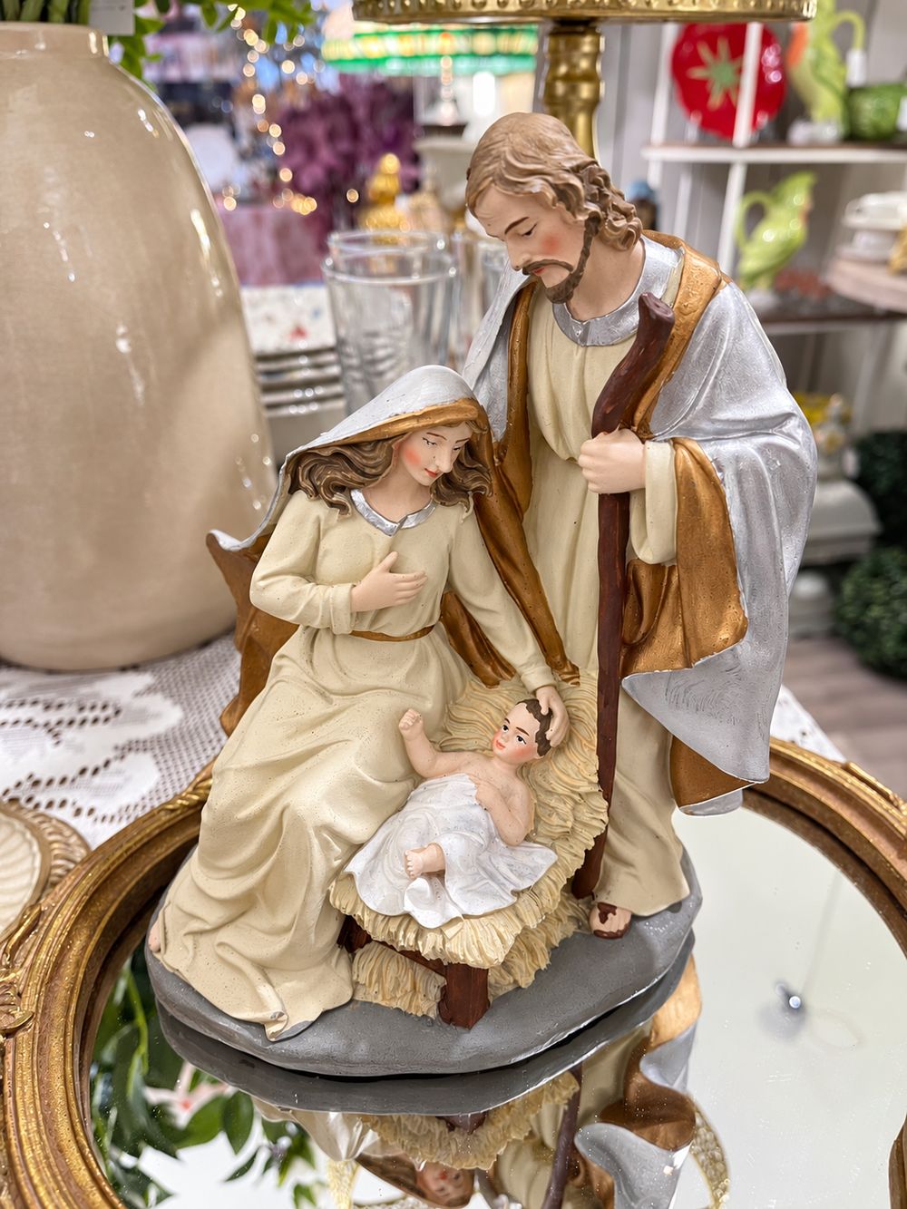 Crèche de Noël en résine crème, dorée et argentée, vue de trois quarts avec Marie, Joseph et l’enfant Jésus.