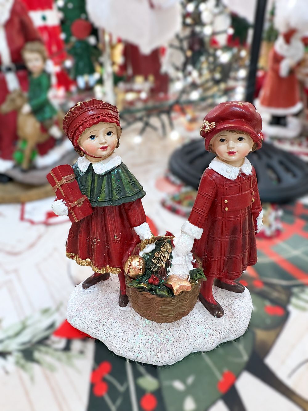 Figurine Enfants au Panier de Noël vue de face, avec panier garni et socle blanc pailleté.