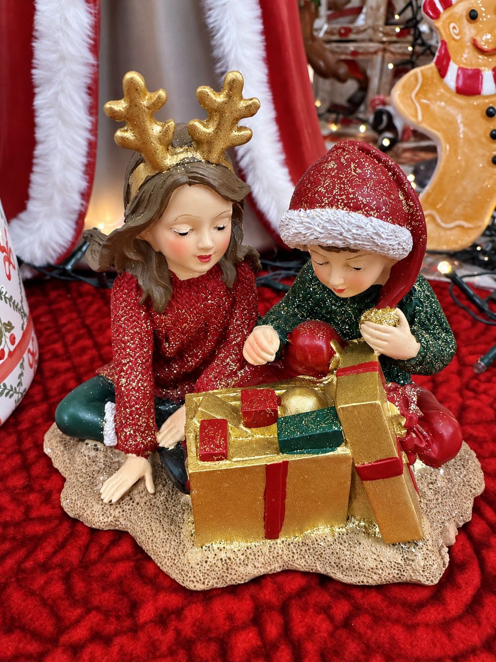 Figurine Les Enfants au Trésor de Noël vue de face, avec deux enfants et leur cadeau doré ouvert.