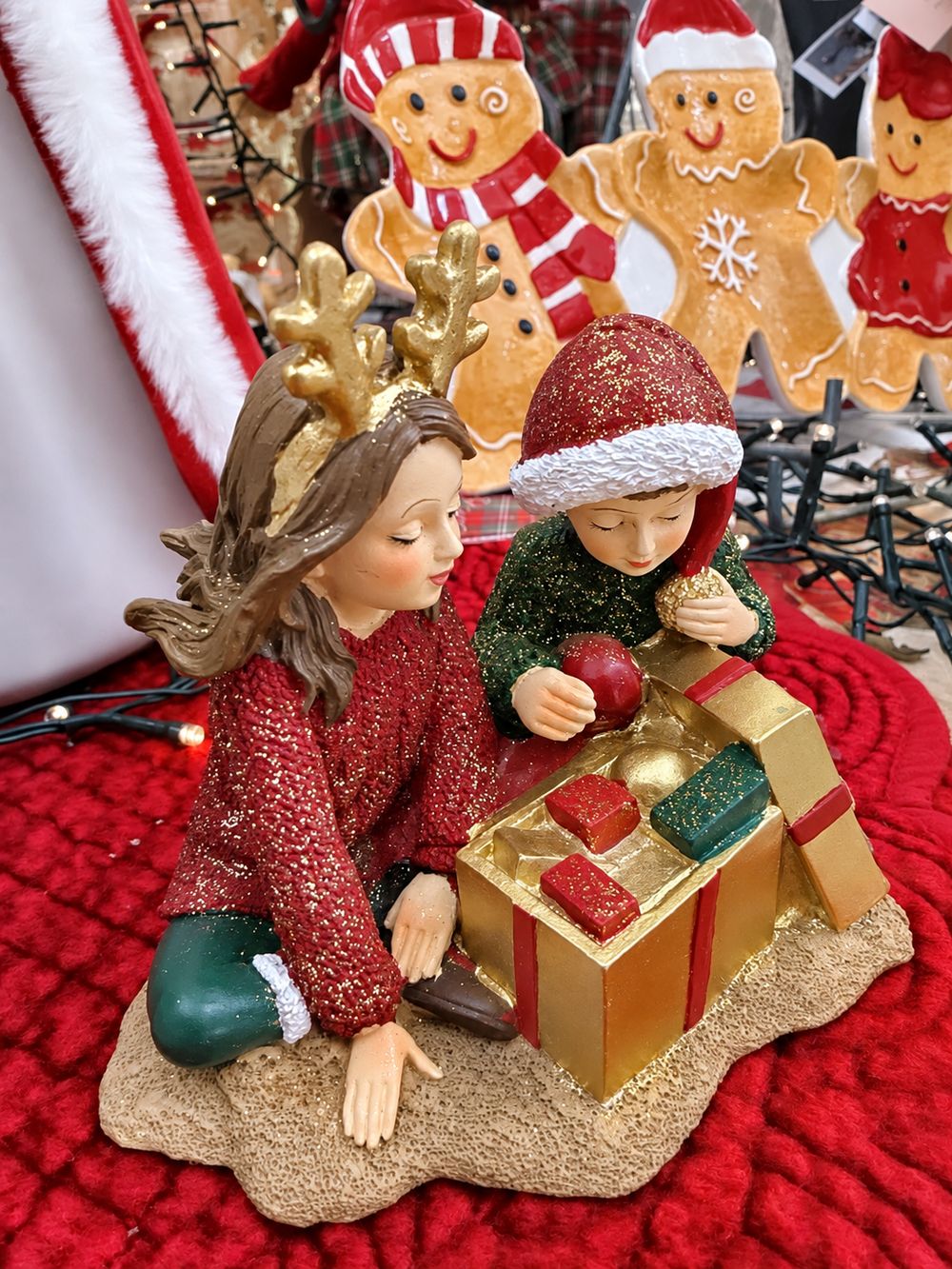 Vue de côté des Enfants au Trésor de Noël, montrant les tenues à paillettes et le contenu du cadeau doré.