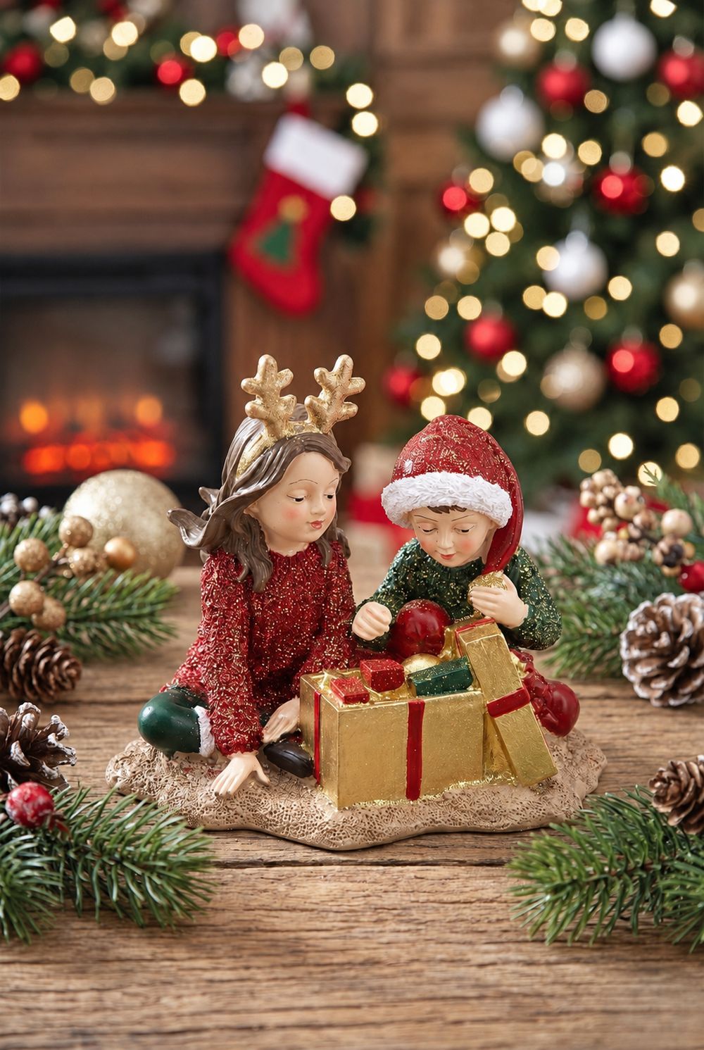 Figurine Les Enfants au Trésor de Noël sur une table en bois, devant un sapin illuminé et une cheminée.
