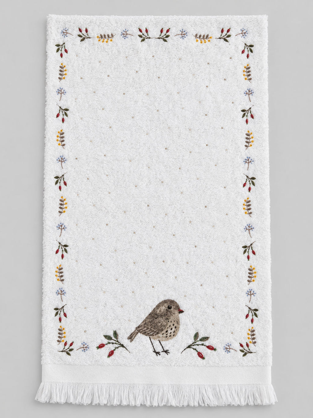 Essuie-mains Petit Oiseau déplié, en coton blanc, avec broderies végétales, oiseau brun et finition frangée.