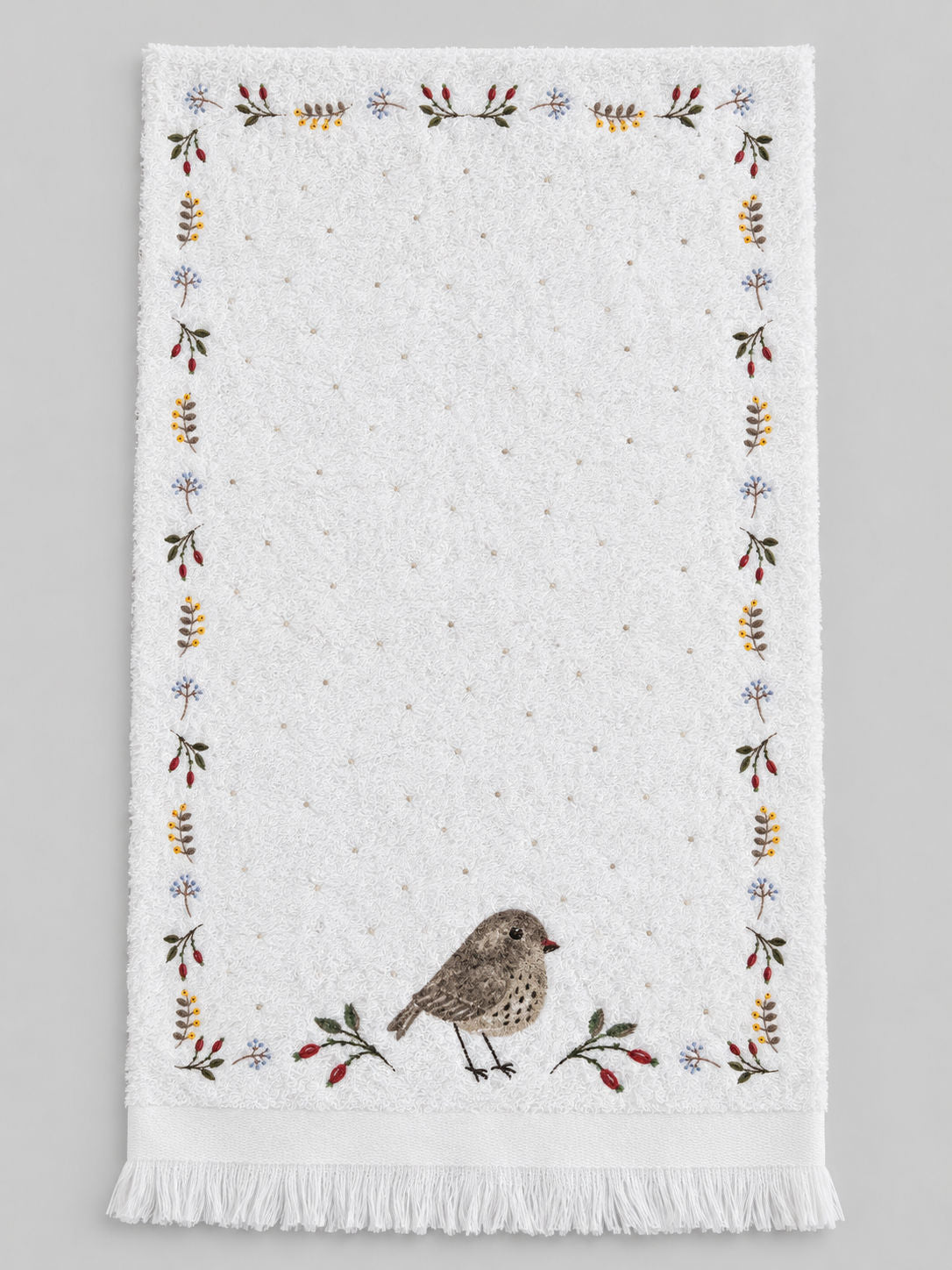 Essuie-mains Petit Oiseau déplié, en coton blanc, avec broderies végétales, oiseau brun et finition frangée.