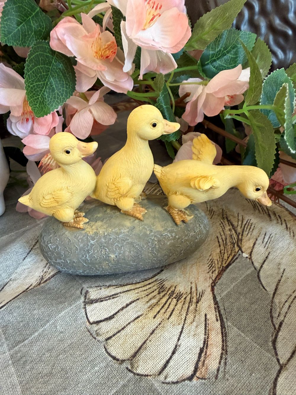 Figurine décorative de trois petits canards jaunes sur socle effet pierre, ambiance printanière et romantique avec fleurs, style shabby chic et décoration de charme