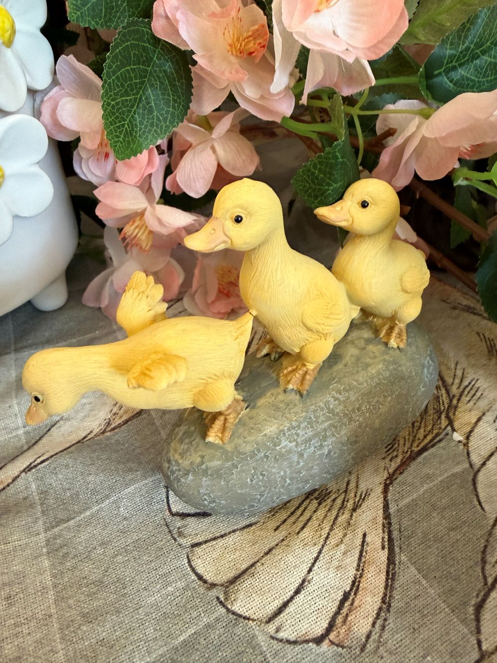 Figurine décorative de trois petits canards jaunes sur socle effet pierre, ambiance printanière et romantique avec fleurs, style shabby chic et décoration de charme