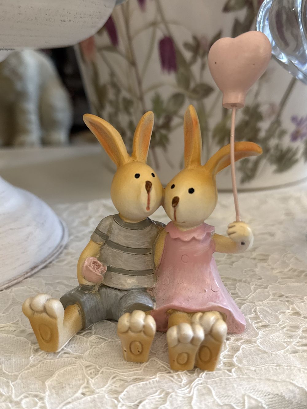 Figurine décorative duo de lapins enlacés avec ballon cœur rose, tons rose poudré et gris, style shabby chic romantique et féérique, ambiance décoration de charme.