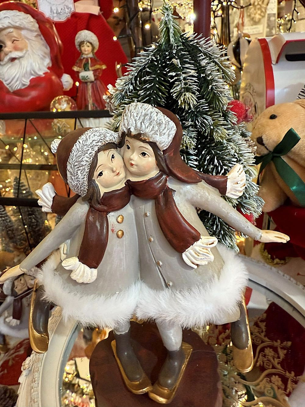 Figurine de Noël représentant deux petites skieuses en gris, blanc et marron, sur socle bois, ambiance hivernale romantique et féérique