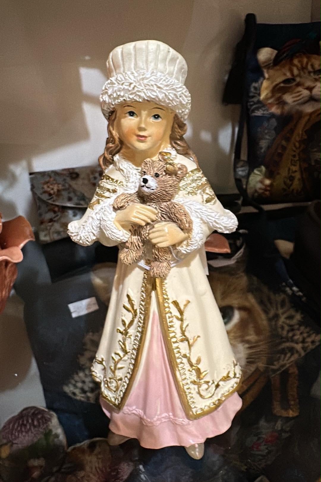 Figurine décorative représentant une fillette de style victorien tenant un ourson, vêtue d'un manteau ivoire brodé et d'une robe rose poudré, idéale pour une décoration romantique et de Noël