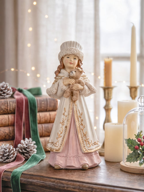 Figurine décorative représentant une fillette de style victorien tenant un ourson, vêtue d'un manteau ivoire brodé et d'une robe rose poudré, idéale pour une décoration romantique et de Noël