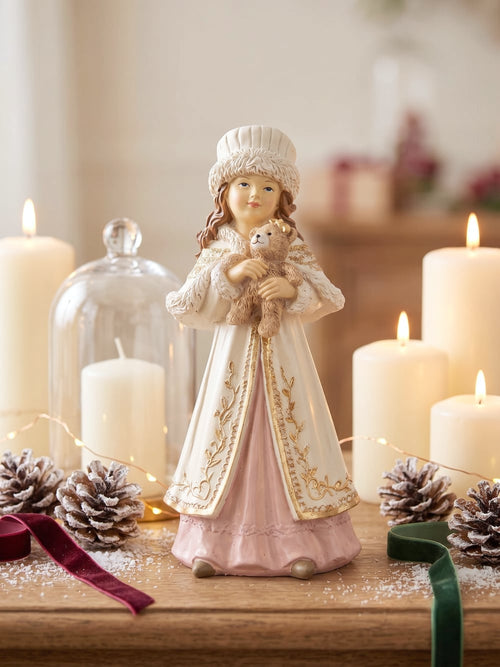 Figurine décorative représentant une fillette de style victorien tenant un ourson, vêtue d'un manteau ivoire brodé et d'une robe rose poudré, idéale pour une décoration romantique et de Noël