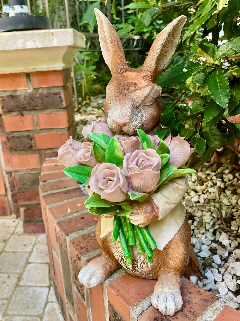Figurine décorative représentant un lapin marron tenant un bouquet de roses rose pastel avec feuillage vert, dans un style shabby chic romantique et poétique