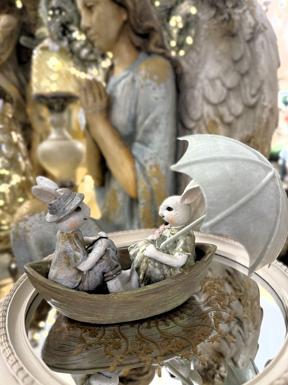 Figurine décorative représentant deux lapins en barque avec ombrelle, tons blanc beige et vert patiné, style shabby chic, ambiance romantique et féérique, décoration poétique de charme