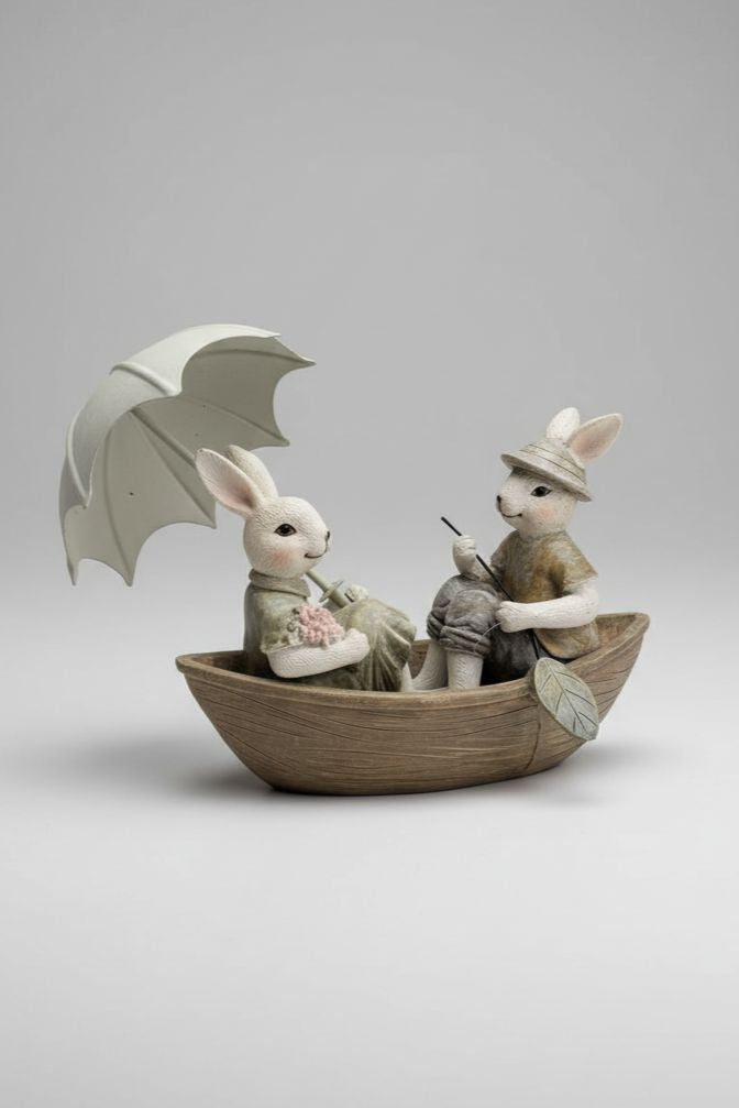 Figurine décorative représentant deux lapins en barque avec ombrelle, tons blanc beige et vert patiné, style shabby chic, ambiance romantique et féérique, décoration poétique de charme
