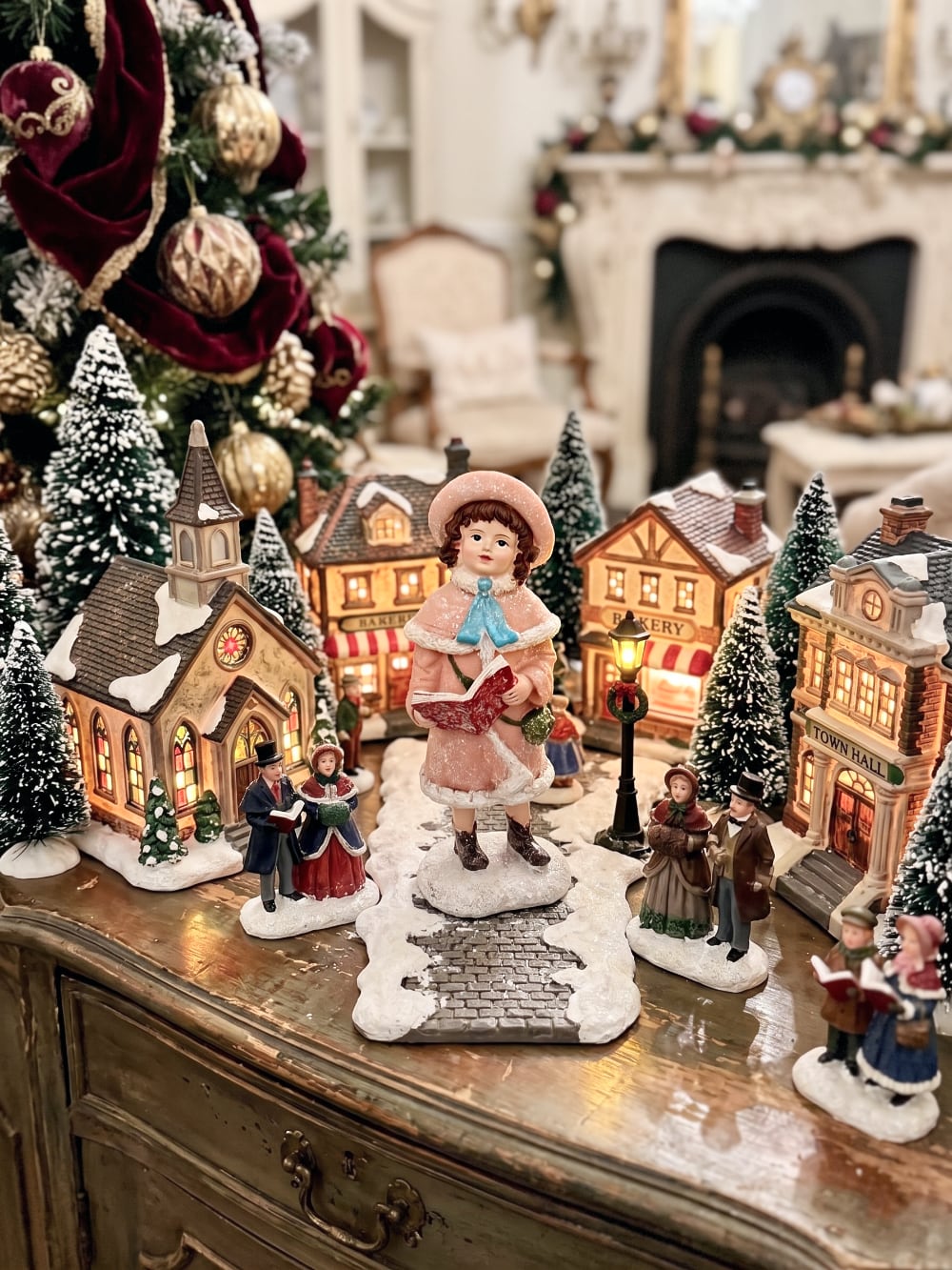 Figurine de Noël représentant une petite chanteuse en manteau rose et bonnet assorti, dans un style victorien romantique, sur fond de décoration shabby chic