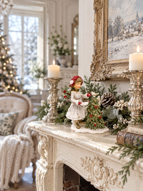 Figurine de Noël petite fille, oiseau et sapin décoré près d’une cheminée