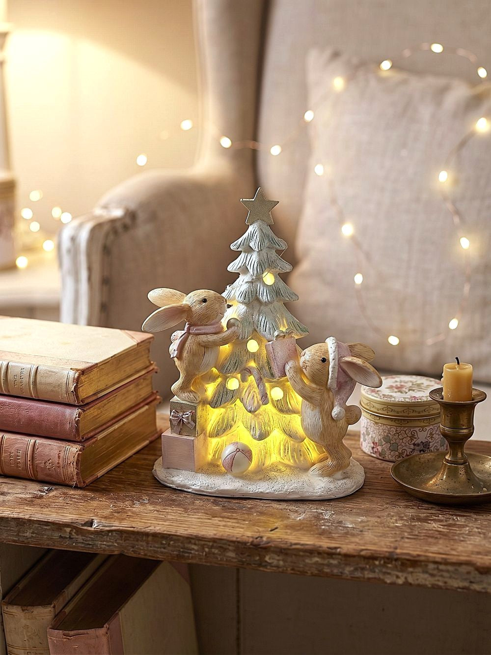 Figurine de Noël avec deux lapinous autour d’un sapin lumineux, tons vert givré, crème et rose poudré, décoration féérique et romantique