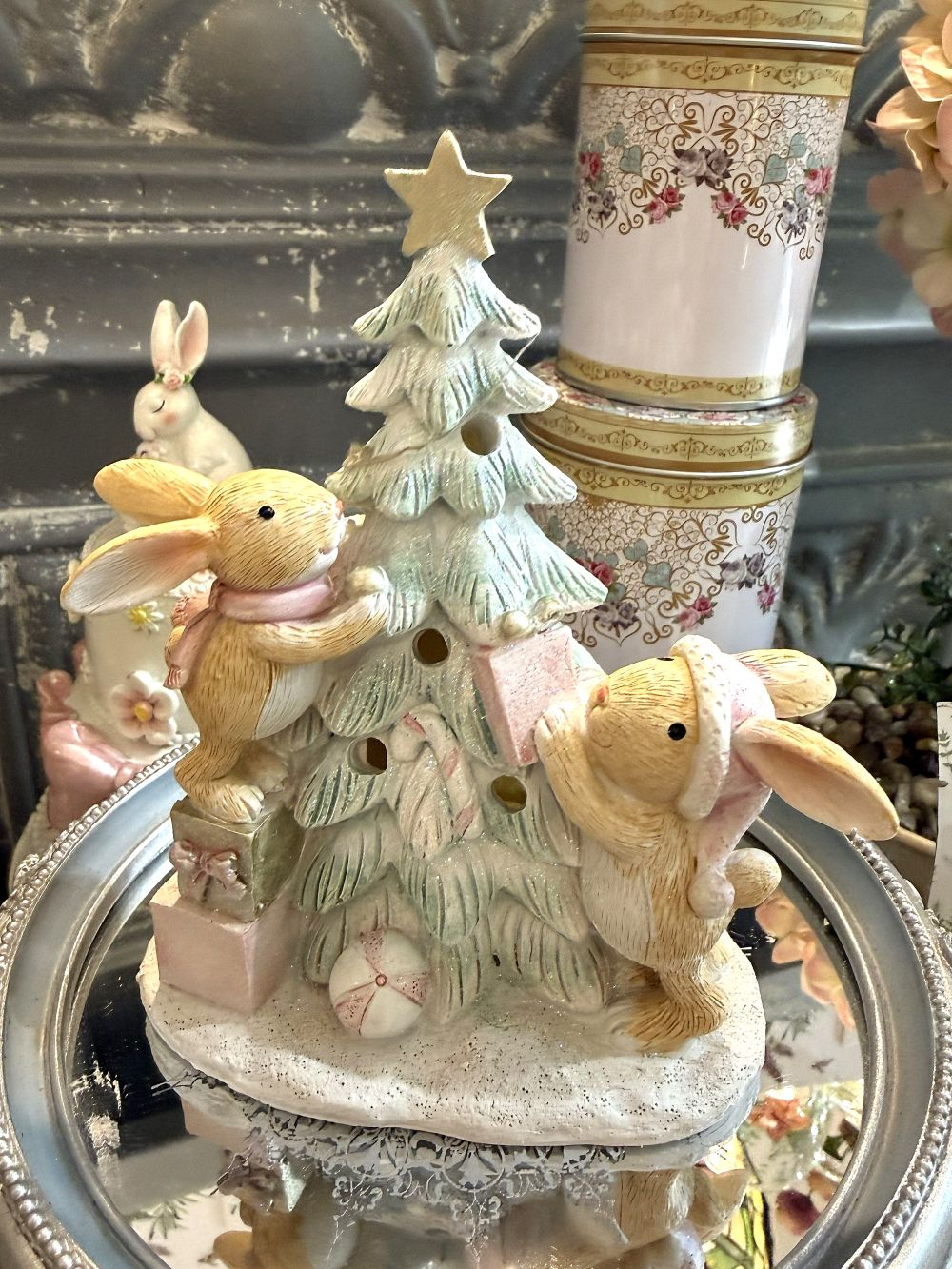Figurine de Noël avec deux lapinous autour d’un sapin lumineux, tons vert givré, crème et rose poudré, décoration féérique et romantique