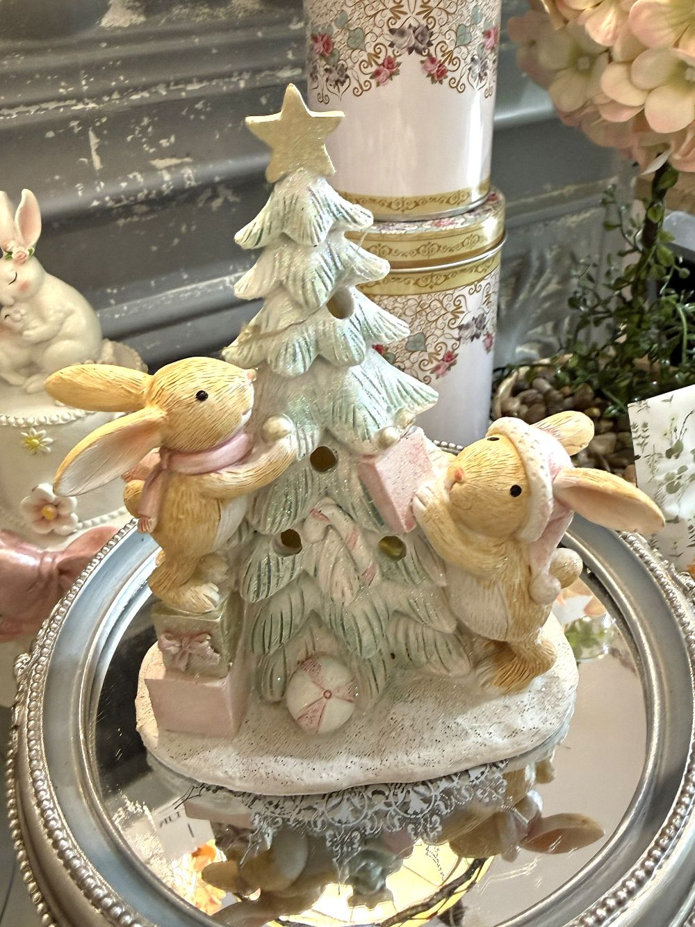 Figurine de Noël avec deux lapinous autour d’un sapin lumineux, tons vert givré, crème et rose poudré, décoration féérique et romantique