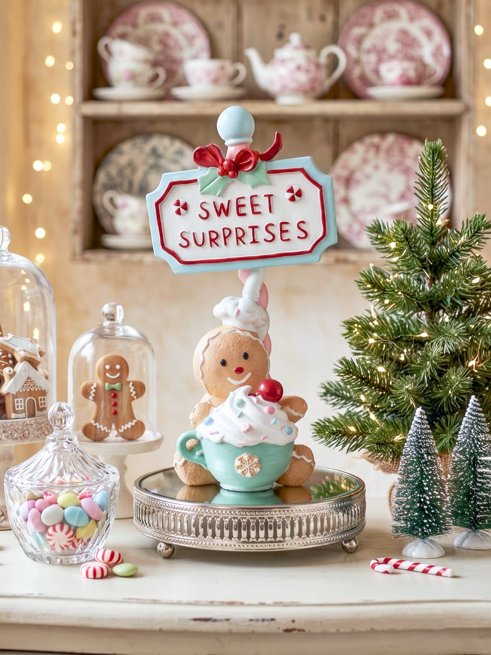Figurine de Noël Sweet Surprise avec personnage biscuit, cupcake, enseigne rétro, teintes caramel, bleu pastel et rouge dans une ambiance gourmande et féérique