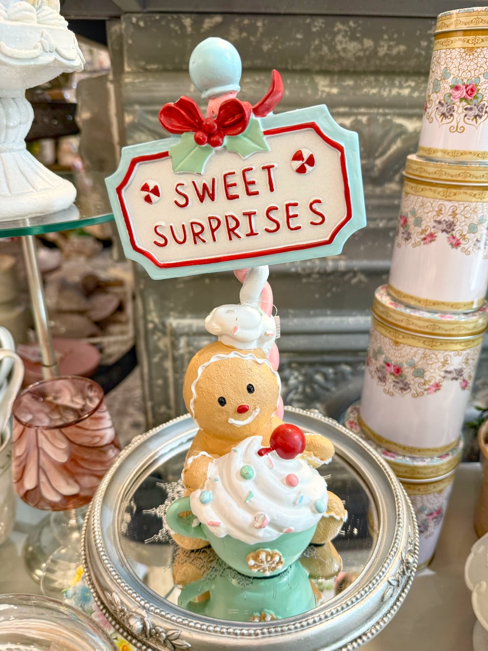 Figurine de Noël Sweet Surprise avec personnage biscuit, cupcake, enseigne rétro, teintes caramel, bleu pastel et rouge dans une ambiance gourmande et féérique