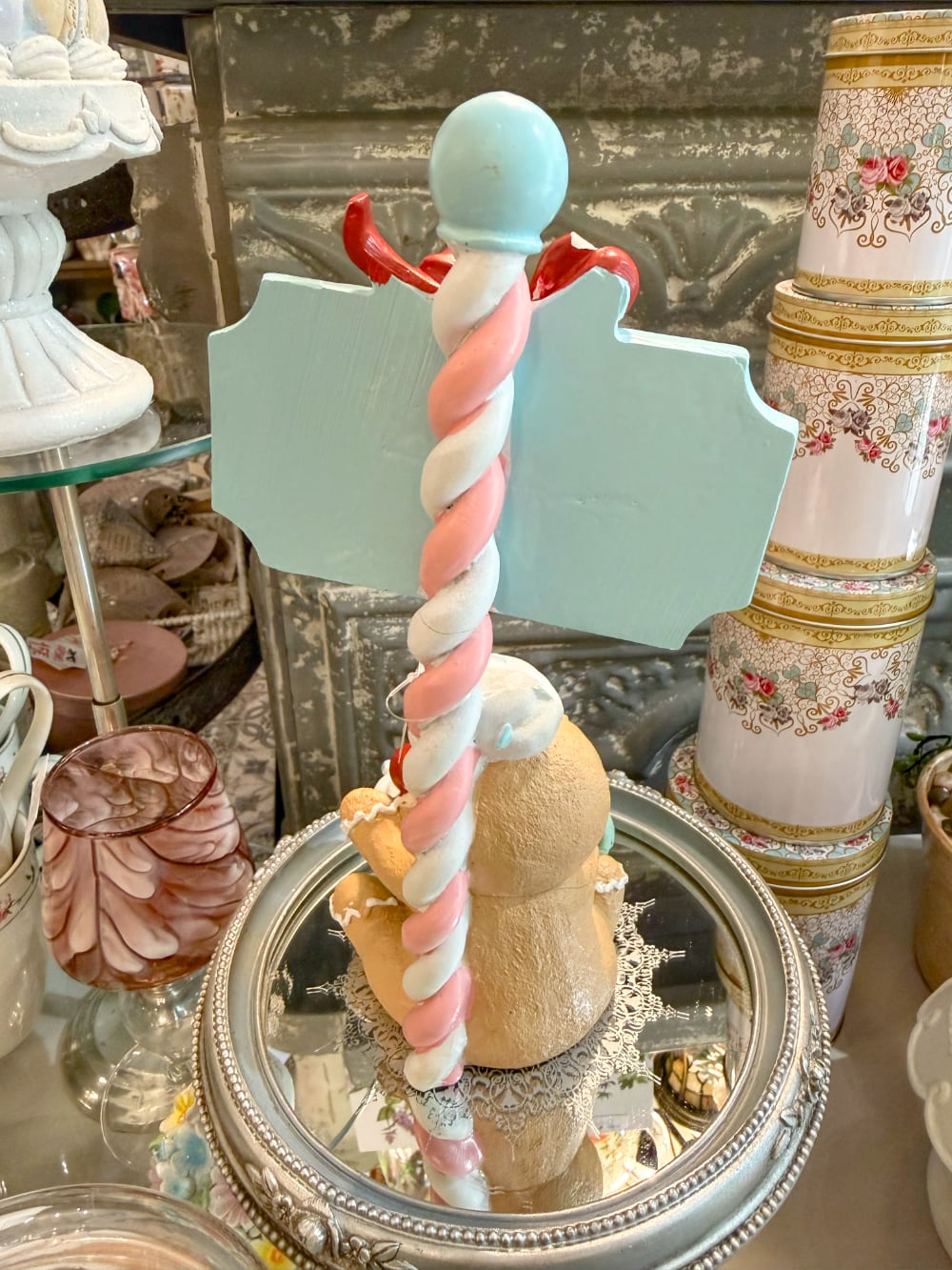 Figurine de Noël Sweet Surprise avec personnage biscuit, cupcake, enseigne rétro, teintes caramel, bleu pastel et rouge dans une ambiance gourmande et féérique