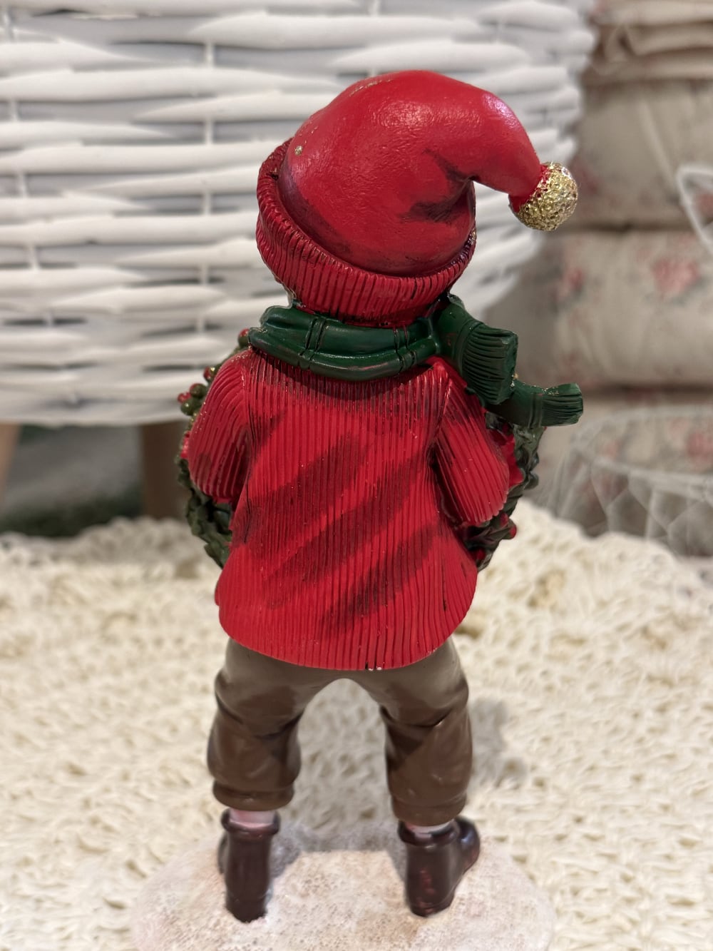 Figurine petit garçon de Noël en rouge et vert tenant une couronne végétale à baies rouges, décoration de Noël poétique et féérique