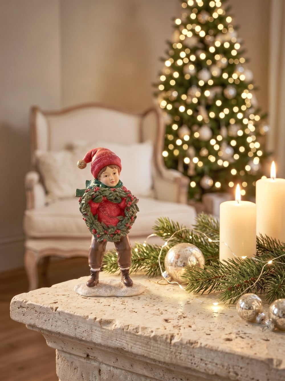 Figurine petit garçon de Noël en rouge et vert tenant une couronne végétale à baies rouges, décoration de Noël poétique et féérique
