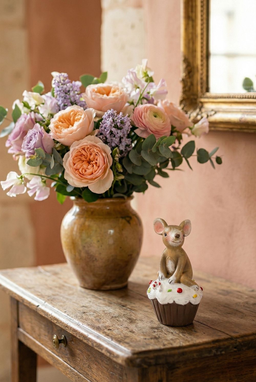 Figurine souris beige assise sur un cupcake blanc décoré, ambiance romantique shabby chic et décoration printanière pleine de charme