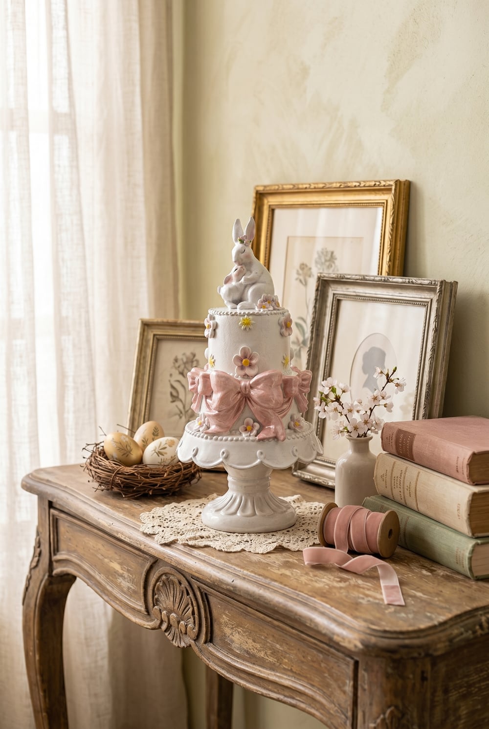 Gâteau décoratif à étages orné de fleurs pastel et de grands nœuds rose poudré avec une maman lapin et son petit au sommet, décoration romantique de Pâques et ambiance féérique