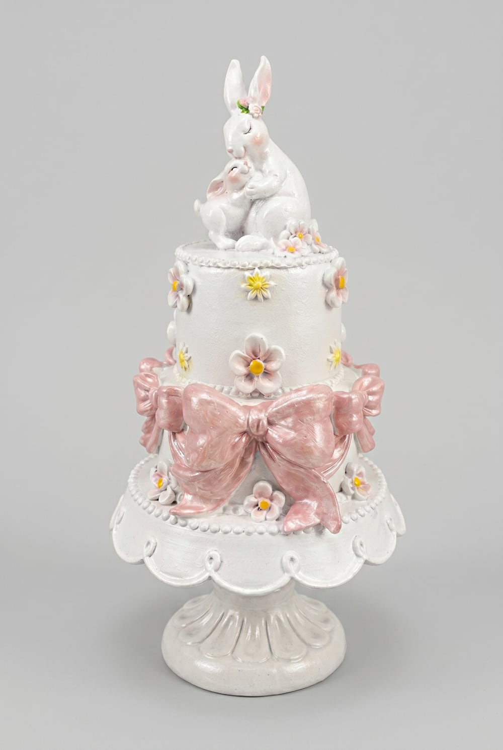 Gâteau décoratif à étages orné de fleurs pastel et de grands nœuds rose poudré avec une maman lapin et son petit au sommet, décoration romantique de Pâques et ambiance féérique