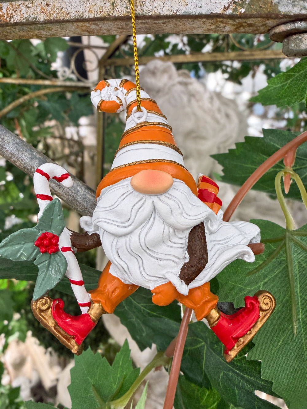 Détail du gnome de Noël à suspendre avec bonnet rayé orange et blanc, longue barbe et canne festive