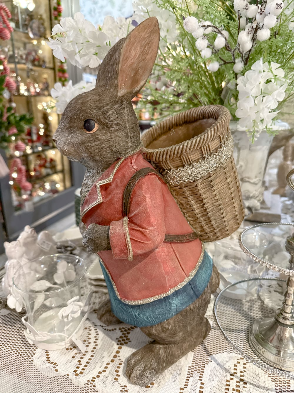 Grand lapin décoratif brun vêtu de rose et bleu avec panier dans le dos, style Alice romantique et décoration poétique de Pâques