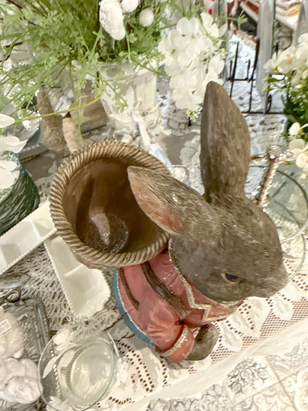 Grand lapin décoratif brun vêtu de rose et bleu avec panier dans le dos, style Alice romantique et décoration poétique de Pâques