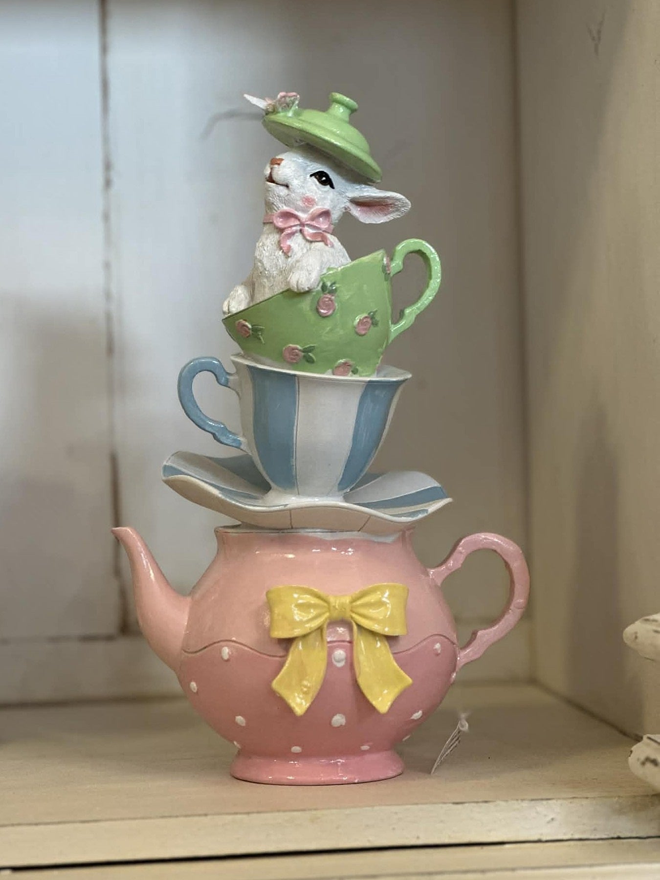 Grande théière décorative rose avec tasses empilées et lapin, tons pastel vert et bleu, style shabby chic romantique et féérique, décoration poétique de charme