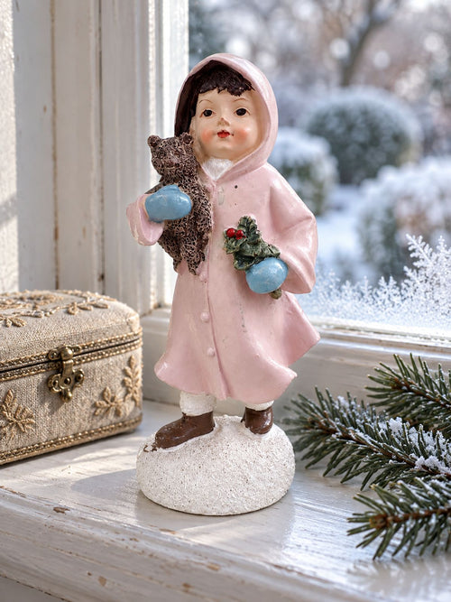 Figurine Héloïse et son ourson sur un rebord de fenêtre, accompagnée d’un coffret et de branches de sapin.