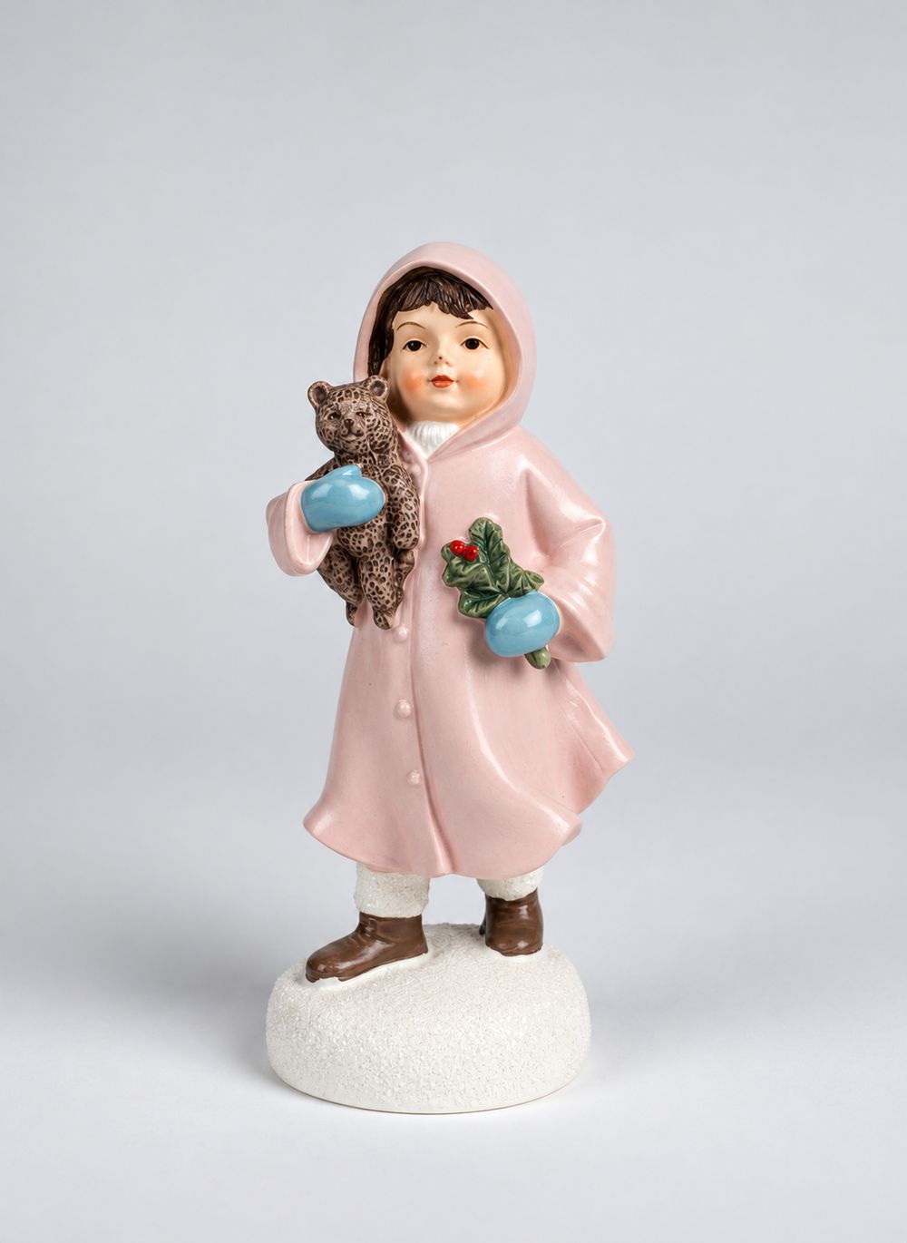 Figurine Héloïse en manteau rose tenant son ourson et un brin de houx, vue de face sur fond gris.