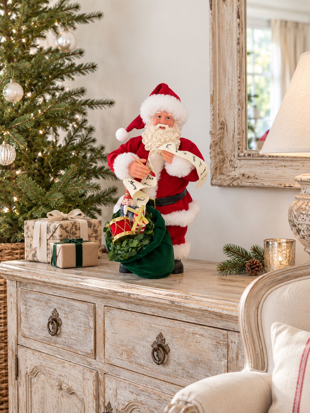 Figurine La lettre au père Noël sur un buffet patiné dans un salon lumineux, avec un sapin décoré et de petits cadeaux.