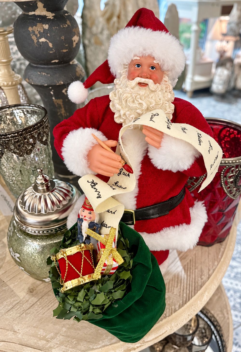 La lettre au père Noël, figurine en costume rouge avec sa liste et son sac de jouets, vue de face.