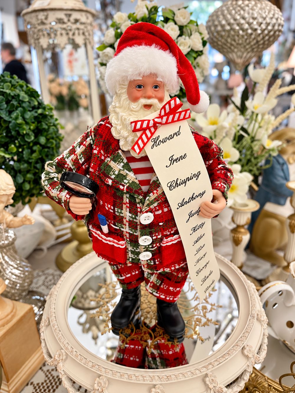 Figurine La liste du Père Noël vue de face, avec son costume à carreaux, sa liste et sa loupe.