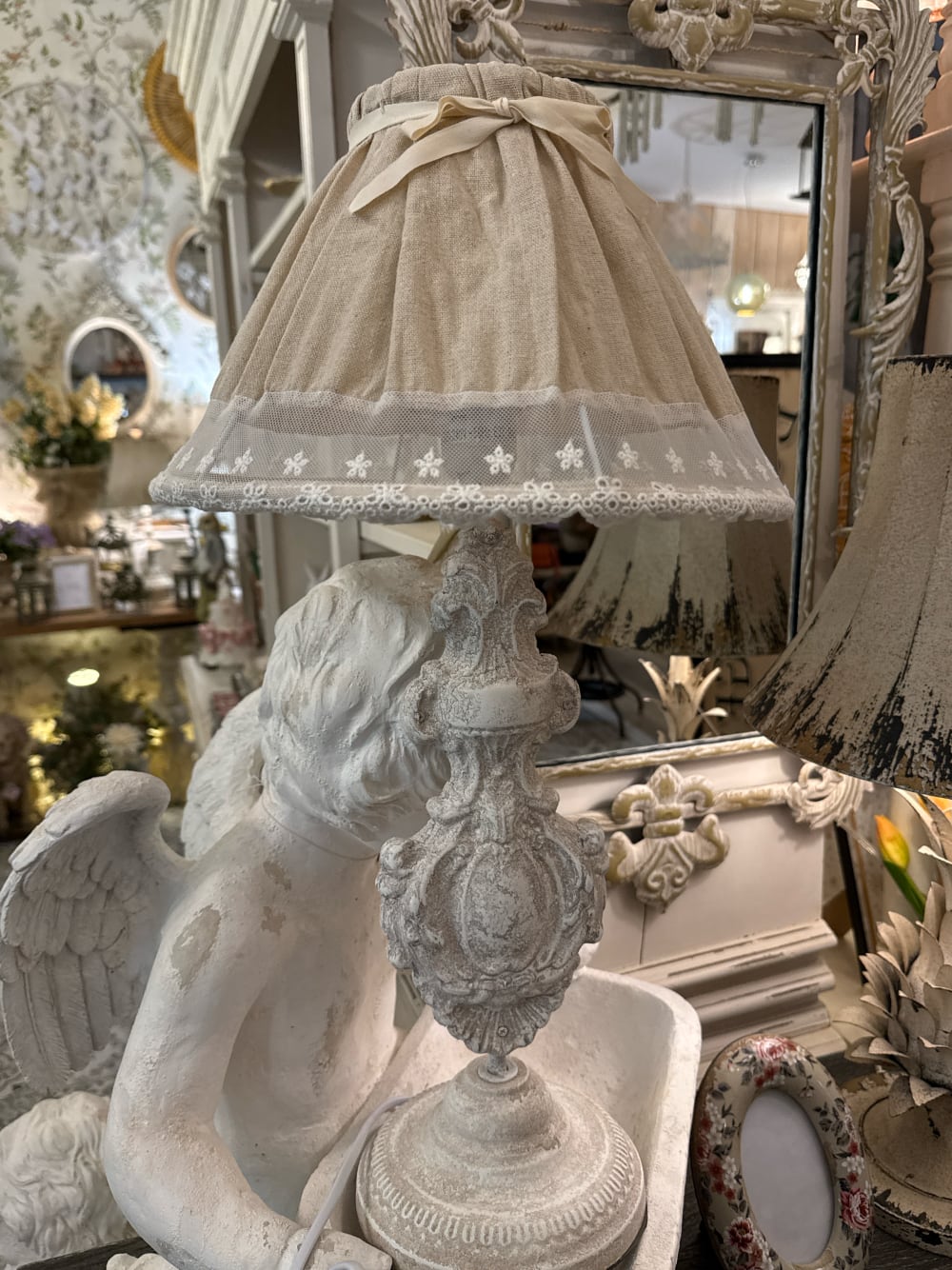 Lampe de table romantique avec pied sculpté blanc patiné et abat-jour en tissu naturel orné de dentelle blanche, idéale pour une décoration shabby chic et de charme