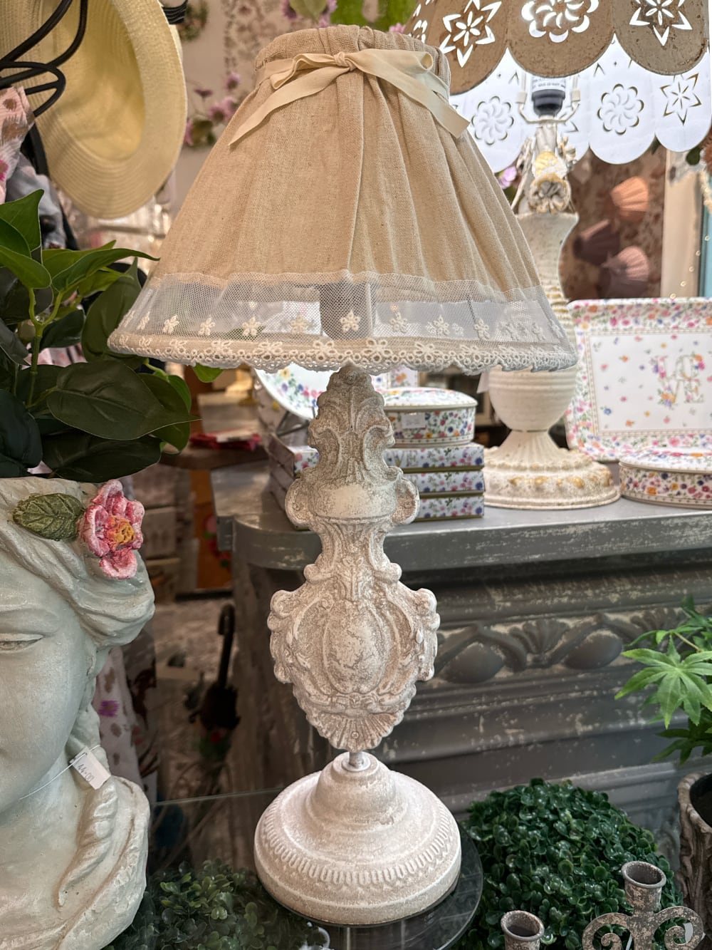 Lampe de table romantique avec pied sculpté blanc patiné et abat-jour en tissu naturel orné de dentelle blanche, idéale pour une décoration shabby chic et de charme