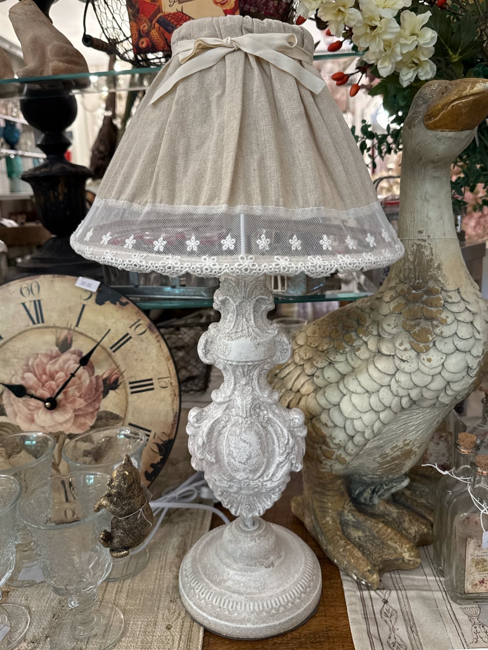 Lampe de table romantique avec pied sculpté blanc patiné et abat-jour en tissu naturel orné de dentelle blanche, idéale pour une décoration shabby chic et de charme