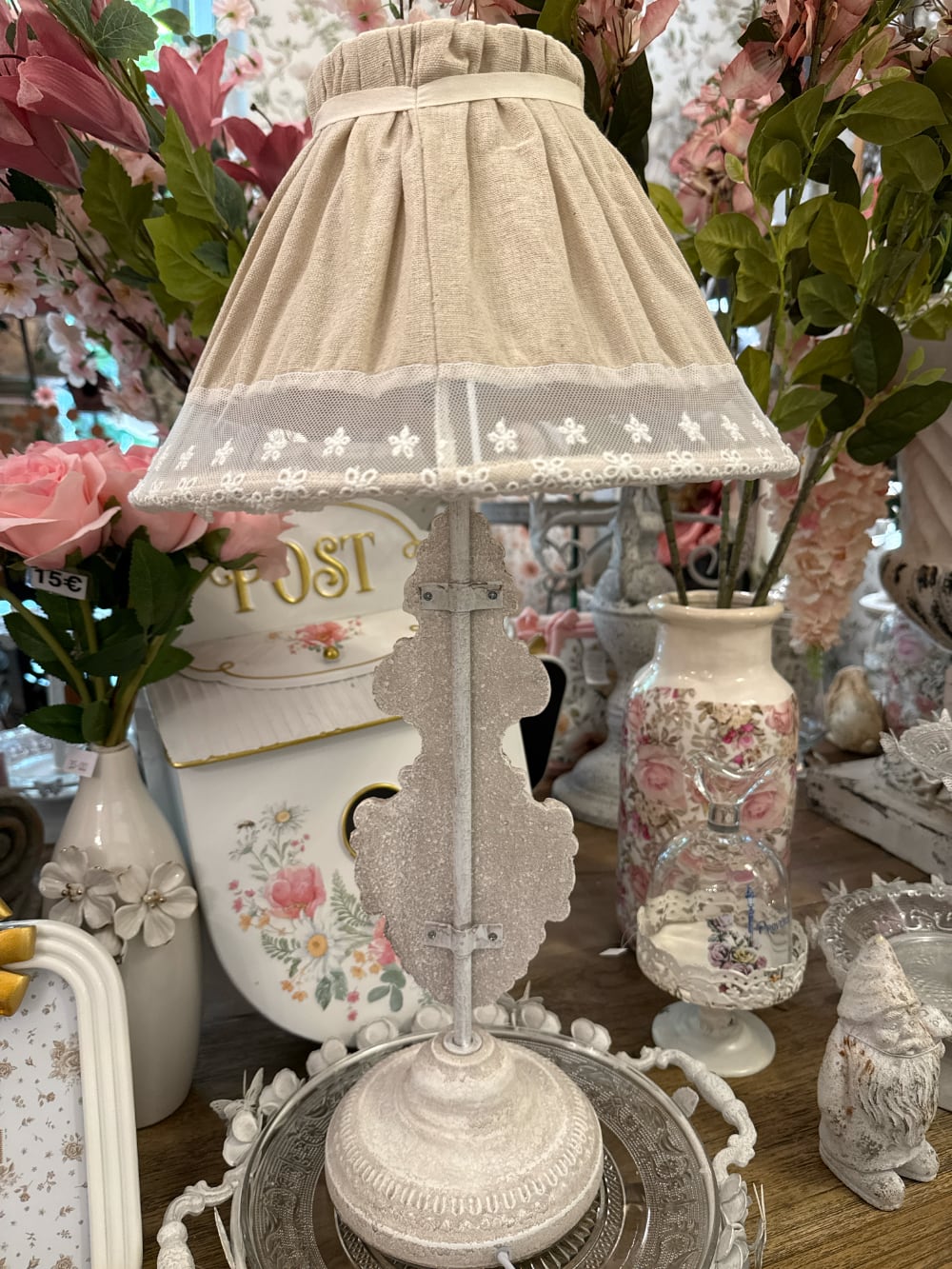 Lampe de table romantique avec pied sculpté blanc patiné et abat-jour en tissu naturel orné de dentelle blanche, idéale pour une décoration shabby chic et de charme