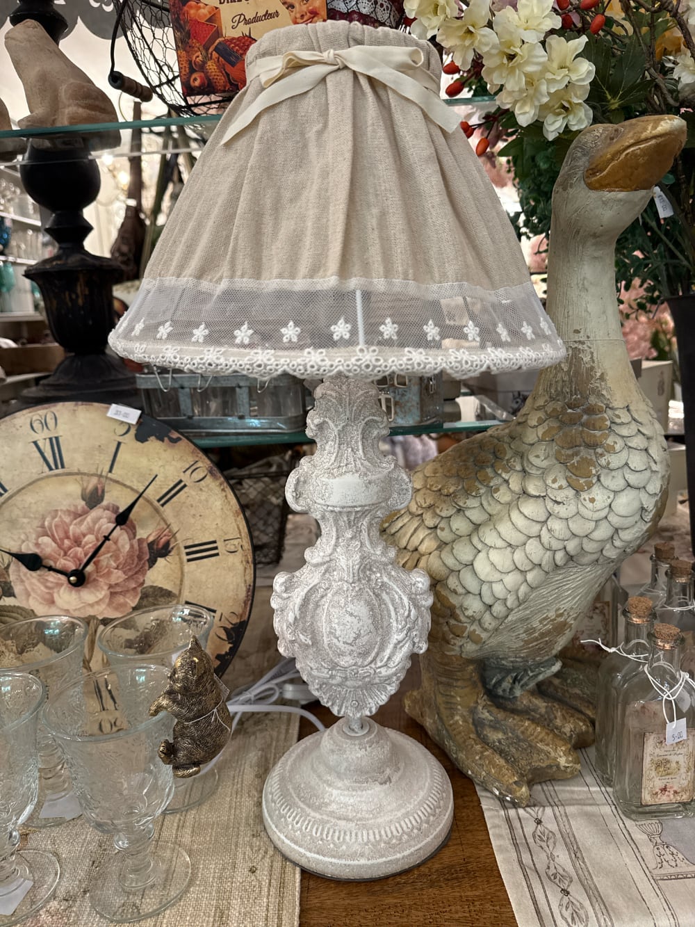 Lampe de table romantique avec pied sculpté blanc patiné et abat-jour en tissu naturel orné de dentelle blanche, idéale pour une décoration shabby chic et de charme