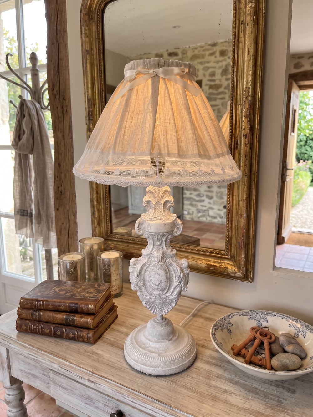 Lampe de table romantique avec pied sculpté blanc patiné et abat-jour en tissu naturel orné de dentelle blanche, idéale pour une décoration shabby chic et de charme