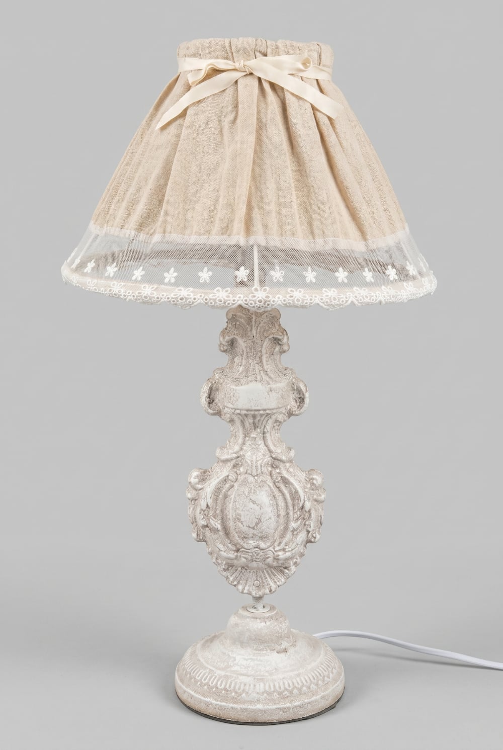 Lampe de table romantique avec pied sculpté blanc patiné et abat-jour en tissu naturel orné de dentelle blanche, idéale pour une décoration shabby chic et de charme