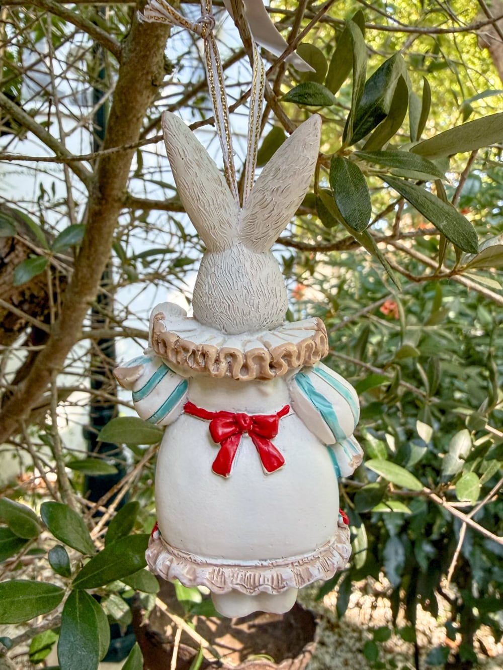 Figurine lapin à suspendre inspirée d'Alice au Pays des Merveilles, avec collerette, tablier à cœur rouge et ruban, idéale pour une décoration de Pâques ou de Noël