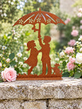 Décoration Les Amoureux au Jardin posée sur un muret en pierre, entourée de roses roses et blanches.